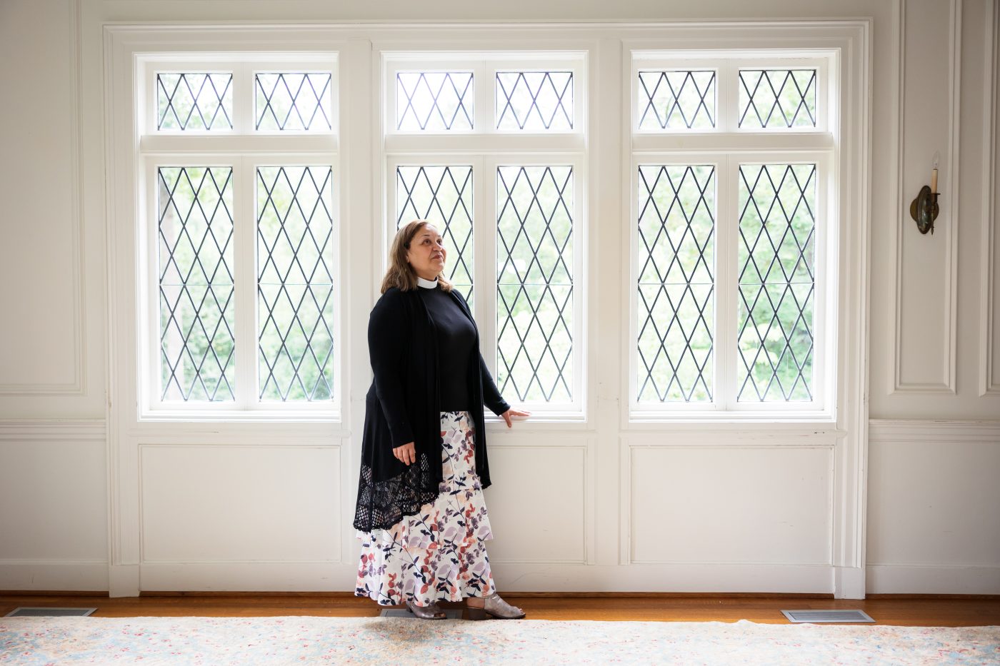A woman standing in front of tall windows